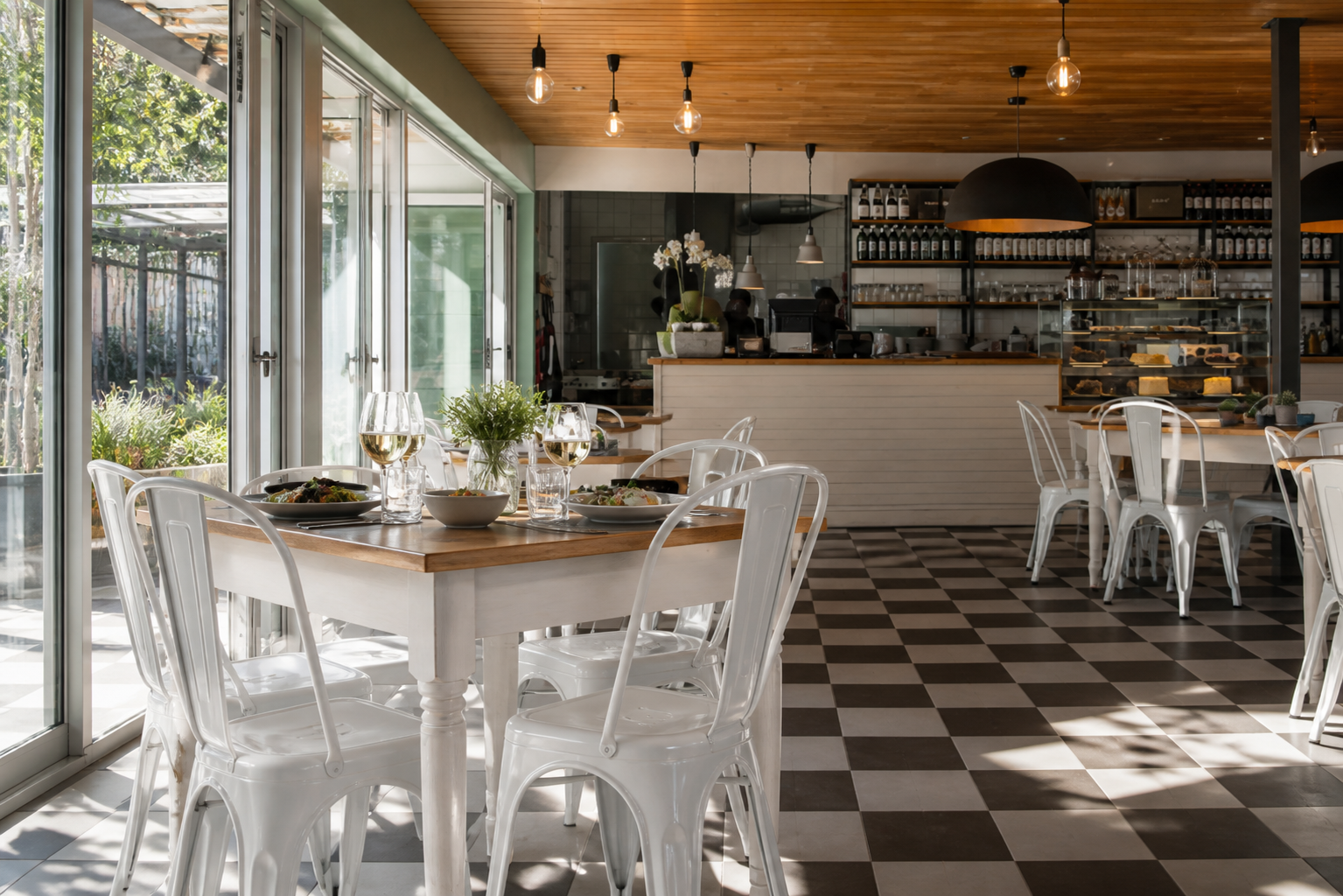 Bright Krisjan's Bistro interior with white café chairs, timber tables and checkerboard floor
